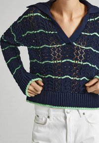 Navy blue knitted sweater with a V-neck and a wide collar. Features green stripes and an openwork design. Ribbed cuffs and hem.