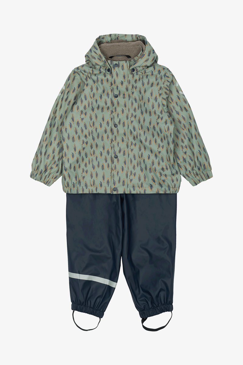 Wodoodporny dwu-elementowy zestaw przeciwdeszczowy z jasne zieloną kurtką w liściasty wzór oraz granatowymi spodniami z odblaskowym paskiem i elastycznymi mankietami.