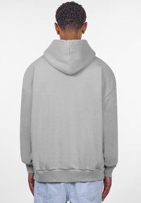 Lys grå oversized hættebluse med en stor hætte, ribbede manchetter og talje, der har en glat tekstur og drop-shoulder-snit.