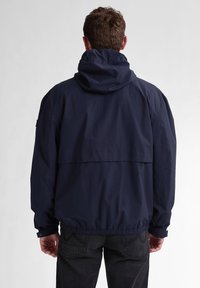 Marineblauwe hoodie met een ontspannen pasvorm, elastische manchetten en zoom. Gemaakt van lichtgewicht stof met een gladde textuur.