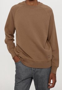 Bruine crewneck sweatshirt met raglanmouwen, geribbelde cuffs en zoom, voorzien van een klein logo-label bij de zoom, gemaakt van een zachte, gestructureerde stof.