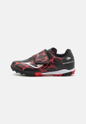 Zapatilla deportiva negra con patrón de llamas rojas, parte superior sintética, correa ajustable, suela de goma con tacos moldeados para tracción y acento de logo en blanco.