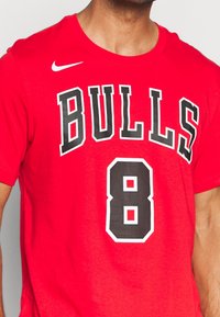 Camiseta de algodón roja con la palabra "BULLS" en letras negras en negrita y el número "8" en un diseño grande, con un contorno blanco y detalles texturizados.