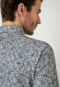 Blumengemustertes Shirt in Blau und Weiß, aus strukturiertem Stoff, mit Kragen und kurzen Ärmeln in taillierter Passform.