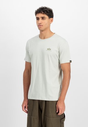 Light green cotton t-shirt with a crew neck, short sleeves, and a small green logo on the chest. Worn with dark green pants.