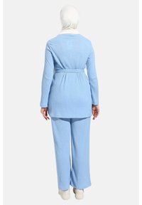 Ljusblå ribbade tvådelade outfit som består av en lång tunika med bälte i midjan och vida byxor. Materialet verkar mjukt och strukturerat.