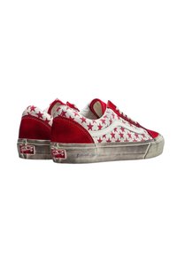 Sneaker rosso e bianco con un motivo a stelle sulla parte superiore in tela, dettagli in suede e una suola in gomma visibilmente usurata.