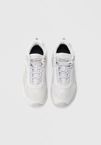 Valged spordijalatsid võrgust ja sünteetilisest materjalist pealiskattega, ümarate varvastega, nöörpaeltega, polsterdatud serva ja tekstuurse kummist tallaga.