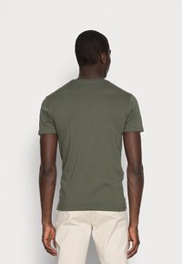 Camiseta de cuello redondo y mangas cortas de color verde oliva, hecha de algodón, diseño ajustado, textura suave, sin patrones ni acentos visibles.