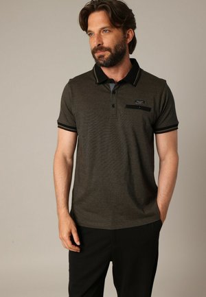 Polo shirt vert foncé avec une finition texturée, col et poignets noirs, patte de boutonnage à trois boutons, et une poche poitrine avec logo.