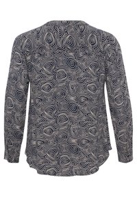 Chemise à manches longues avec un motif concentrique irrégulier de cercles et carrés noir et blanc, vue de dos.