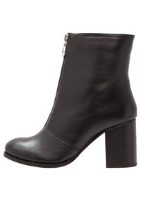Černá kožená kotníková bota s kulatou špicí, bočním zipem a robustním podpatkem. Hladká textura s minimálními švy.