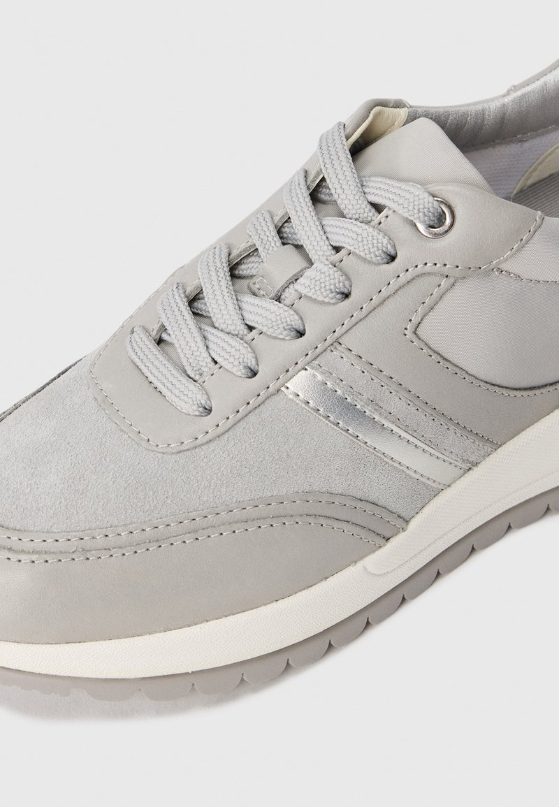 Scarpa sportiva grigia realizzata con una combinazione di suede e pelle liscia, con lacci testurizzati e suola in gomma bianca. Strisce accento argentate aggiungono un tocco di dettaglio.