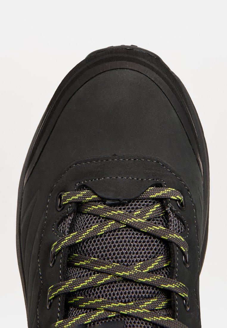 Scarpa da trekking nera con lacci grigi e verdi neon a motivo e tessuto in rete sotto i lacci, vista dall'alto focalizzandosi sulla punta.