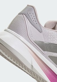 Svetlosivá športová obuv so štruktúrovaným zvrškom, hladkými detailmi, vzorovaným pätovým dielom a strednou podrážkou s prechodom z ružovej do bielej farby a gumovým dezénom.