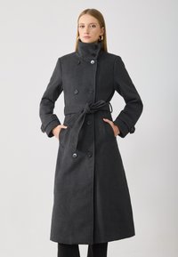 Double-breasted, long grey coat with a high collar, belt tied at the waist, featuring button accents and side pockets. Smooth texture.