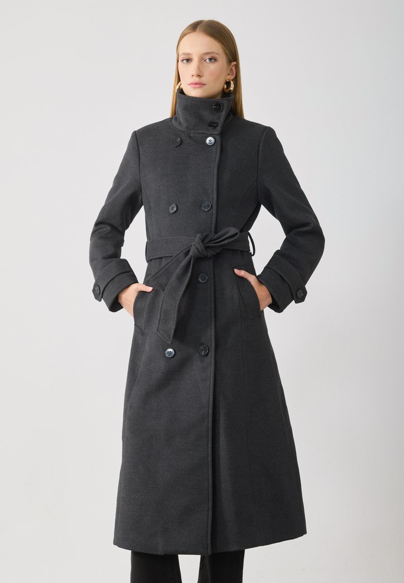 Double-breasted, long grey coat with a high collar, belt tied at the waist, featuring button accents and side pockets. Smooth texture.