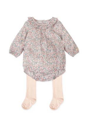 Blusa floral con cuello rizado en rosa pastel, con mangas largas y un dobladillo redondeado. Combinada con medias ligeras de color beige.