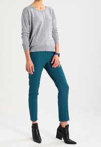 Grijze gebreide trui, teal broek met slim fit en enkel lengte, zwarte enkelboots met hak, casual outfit met een eenvoudig ontwerp.