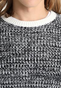 Maglione lavorato a maglia in bianco e nero con scollo rotondo e motivo testurizzato, con colletto bianco a coste.