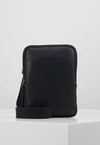 Borsa a tracolla in pelle nera con chiusura a zip, forma piatta, superficie texturizzata e un piccolo logo decorativo. Presenta una tracolla regolabile.