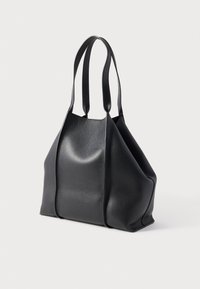 Melna ādas tote soma ar fakturētu virsmu, divām siksnām un plašu, vaļēju formu. Raksturīga bezšuvju konstrukcija un minimālas detaļas.