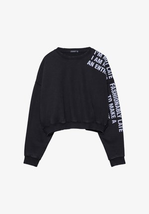 Black cropped sweatshirt made of cotton blend, features long sleeves, a round neckline, and white text along the left sleeve.