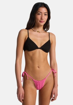Top de bikini negro acanalado con tirantes ajustables, combinado con braguitas de bikini rosas con fruncidos y cierres laterales con lazos.