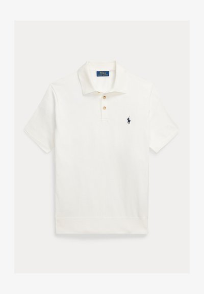 Baltas polo marškinėlis su sagomis priekyje, trumpomis rankovėmis ir mažu tamsiai mėlynu logotipu kairėje krūtinės pusėje. Pagamintas iš medvilnės audinio su lygiu paviršiumi.