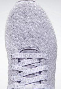 Chaussure de sport violet clair avec un motif en maille texturée en zigzag, des lacets plats et une languette rembourrée, dotée d'une semelle en caoutchouc blanche.