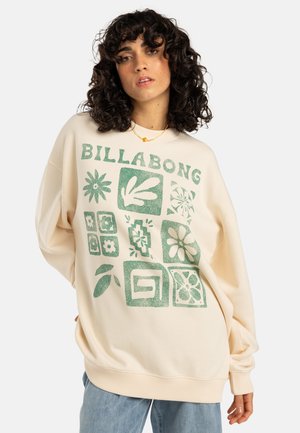 Felpa color crema con stampa grafica verde di fiori e forme, caratterizzata da un collo e polsini a costine. Vestibilità casual oversized.