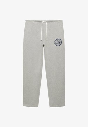 Pantaloni della tuta grigio chiaro con coulisse bianca e un piccolo emblema circolare blu scuro sulla coscia destra, con testo e grafiche.