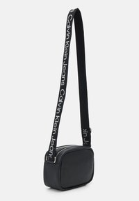 Borsa a tracolla nera di forma rettangolare, realizzata in materiale liscio, con una tracolla con logo a contrasto e chiusura con zip.