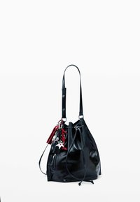 Fekete bőr vödrös táska állítható vállpánttal, zsinóros záródással és több díszes piros és ezüst kulcstartóval ellátva.