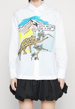 Chemise blanche à col avec un graphisme représentant un léopard se reposant sur une branche d’arbre avec des montagnes et une bulle de dialogue disant "Let's be lazy for a day."