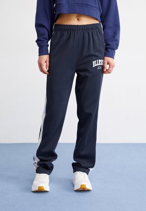 Marineblå joggebukser med hvite side-striper og 'ELLESSE'-logo på venstre lår, med elastisk linning og en avslappet passform.