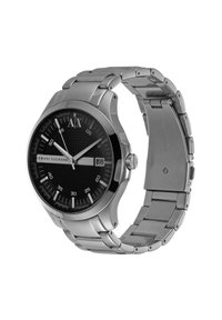 Reloj de acero inoxidable con un dial negro texturizado, manecillas de hora y minuto plateadas, ventana de fecha y una pulsera de eslabones. Logo situado a las 12 en punto.