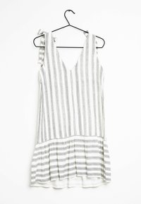 Vestido blanco con rayas verticales negras, escote en V y tirantes ajustables con lazo. Hemd flared con un borde rizado en la parte inferior.