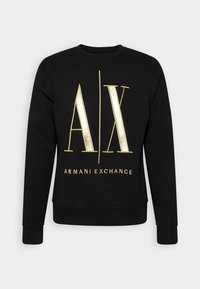 Sudadera negra con cuello redondo y mangas largas. Presenta un logo metálico dorado "AX" y el texto "ARMANI EXCHANGE" en la parte delantera. Material de algodón.
