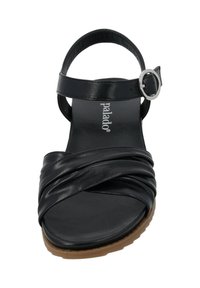 Schwarze Leder-Sandale mit überkreuzten Riemen, verstellbarem Knöchelriemen mit einer metallischen Schnalle und einer braunen Gummisohle.