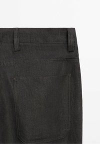 Tummanharmaat farkut, joissa on yksinkertainen takaosa, jossa yksi päällystetasku ja hienovaraiset ompeluajat saumoissa.