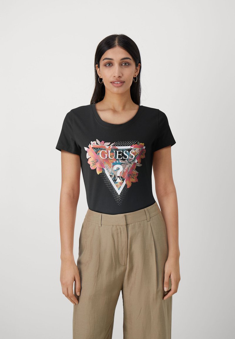 T-shirt noir à manches courtes avec un graphique floral coloré à l'intérieur d'un triangle et le texte "GUESS®" en blanc. Matière en coton lisse.