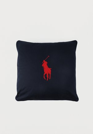 Coussin carré bleu marine avec un joueur de polo rouge brodé à cheval centré sur le devant.