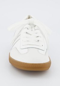 Sneaker bianco con una parte superiore liscia in materiale sintetico, lacci bianchi piatti e una suola in gomma marrone chiaro con un motivo testurizzato.