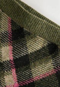 Grüner Wollstoff mit einem schwarzen, cremefarbenen und rosafarbenen Argyle-Muster sowie einem gerippten Strickrand.