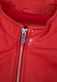 Rote Lederjacke mit hohem Kragen, silberner Reißverschlussöffnung und glatter Textur. Das Innenfutter ist aus passendem roten Stoff.