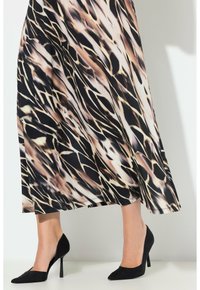 Černé lodičky s vysokým podpatkem a špičatou špičkou, doplněné o splývavou sukni s vícebarevným abstraktním vzorem v krémové, béžové a černé barvě.