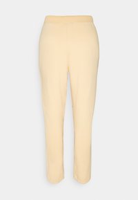 Pantalon beige fuselé avec une taille élastique, fabriqué dans un tissu lisse, présenté sur un fond clair uni.