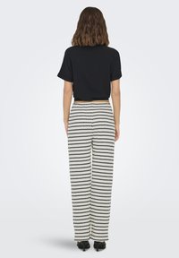 T-shirt nera cropped con maniche corte abbinata a pantaloni larghi a righe nere e bianche. Scarpe col tacco nere.