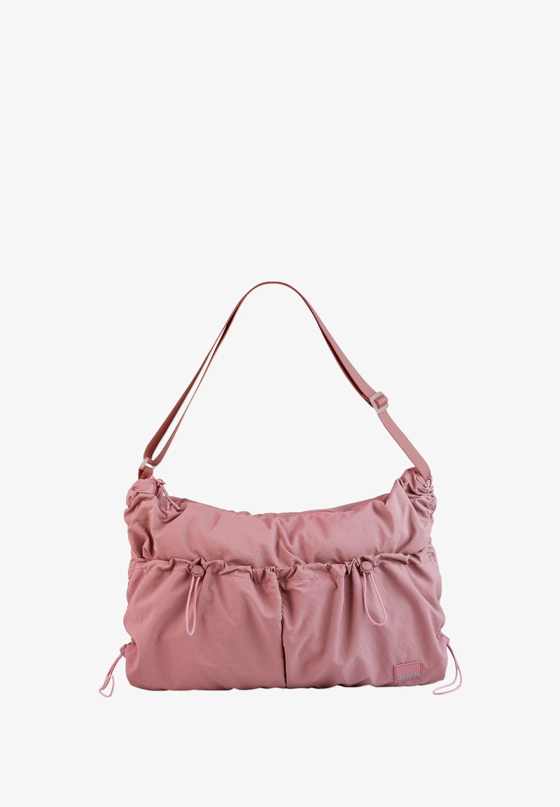 Pink fabric shoulder bag with a gathered design, featuring two front pockets, adjustable strap, and subtle brand tag. Smooth texture.
